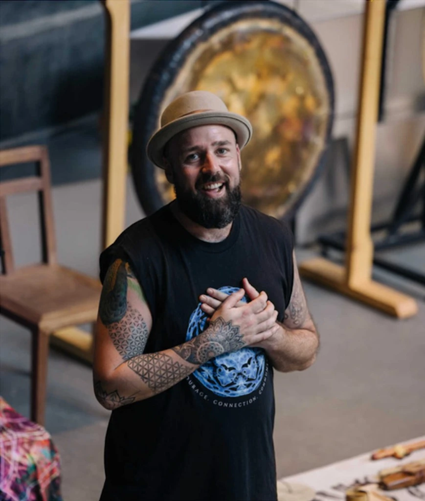 Dan Byrne standing with hands over his heart in front of a large gong